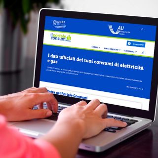 Utente consulta Portale Consumi Arera su laptop, monitor con dati ufficiali consumi energia elettrica e gas, homepage sito...
