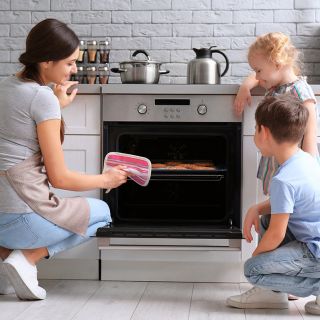 Mamma cucina biscotti con due bambini in cucina moderna, concetto di risparmio energetico e comfort domestico