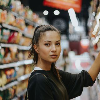 Donna giovane fa la spesa in supermercato, scelta prodotti sugli scaffali, risparmio spesa intelligente, confronto prezzi