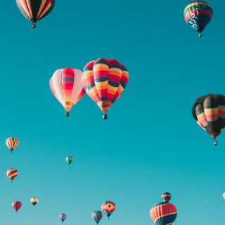 Mongolfiere colorate che si alzano in cielo limpido, concetto di aumento prezzi bollette e opportunità di risparmio