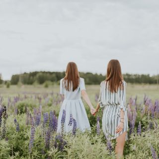 Due donne camminano in un campo di fiori viola, vista posteriore, concetto di libertà e nuove scelte
