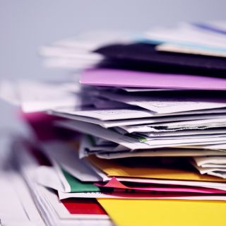 Pila di bollette cartacee multicolore su scrivania, concetto di passaggio a bolletta elettronica ecologica