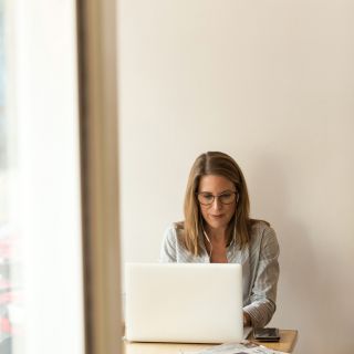 Donna lavora al computer portatile con bollette e giornali sul tavolo, concetto risparmio energetico e gestione spese dome...