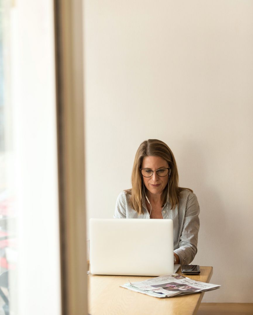Donna lavora al computer portatile con bollette e giornali sul tavolo, concetto risparmio energetico e gestione spese dome...