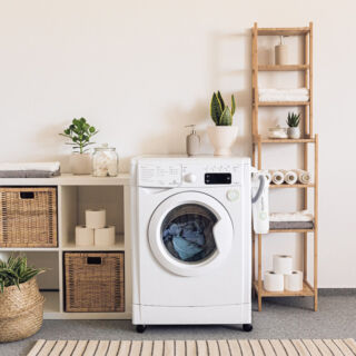 Lavatrice a risparmio energetico classe A+++ in ambiente domestico moderno con piante, scaffali e accessori bagno