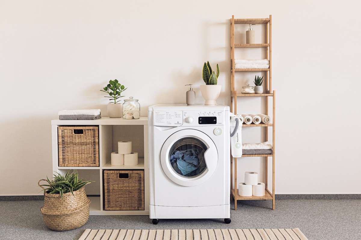 Lavatrice a risparmio energetico classe A+++ in ambiente domestico moderno con piante, scaffali e accessori bagno