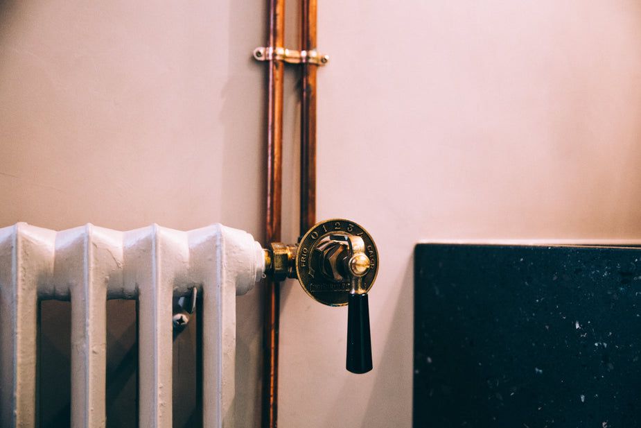 Termostato in ottone su termosifone bianco, dettaglio regolazione riscaldamento domestico per risparmio energetico