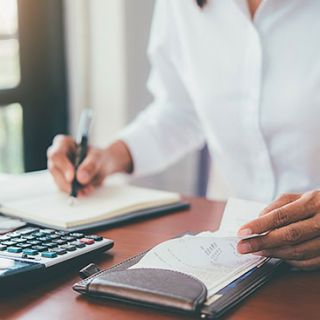 Donna controlla bolletta gas con calcolatrice e blocco appunti, concetto bonus gas famiglie a basso reddito