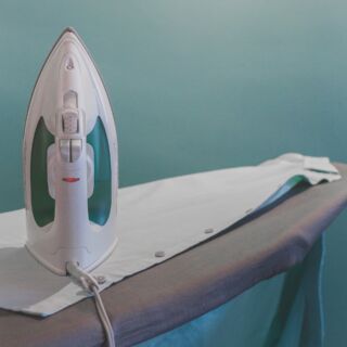 Ferro da stiro acceso su asse con camicia bianca, risparmio energetico e buone abitudini domestiche
