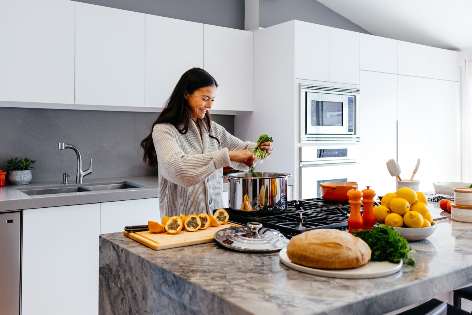 Donna cucina in cucina moderna, prepara verdure fresche per risparmio energetico e consigli su uso razionale del gas domes...