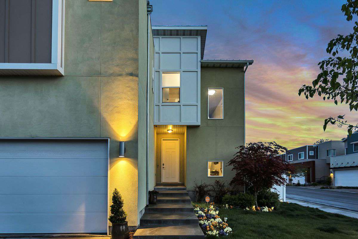 Facciata casa moderna illuminata al tramonto, esempio di riqualificazione energetica e isolamento termico residenziale
