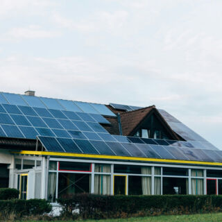 Casa con pannelli solari sul tetto, esempio di produzione energia pulita per comunità energetiche, cielo nuvoloso sullo sf...