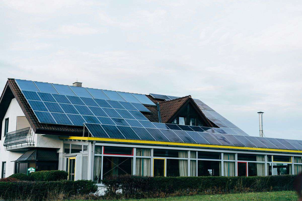Casa con pannelli solari sul tetto, esempio di produzione energia pulita per comunità energetiche, cielo nuvoloso sullo sf...