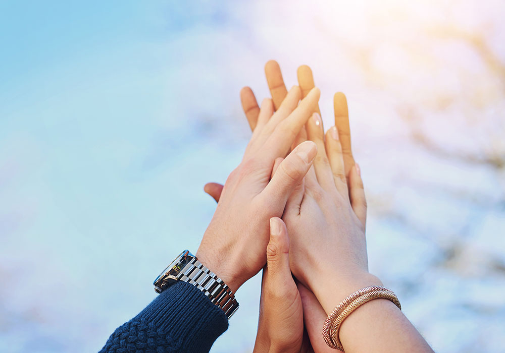 Mani di persone unite verso l’alto, simbolo di collaborazione e comunità energetica sostenibile
