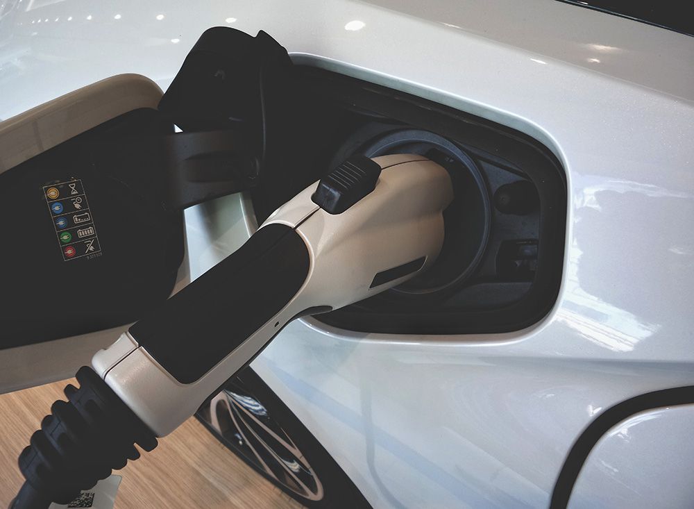 Auto elettrica in ricarica tramite colonnina, dettaglio presa di corrente per riqualificazione energetica
